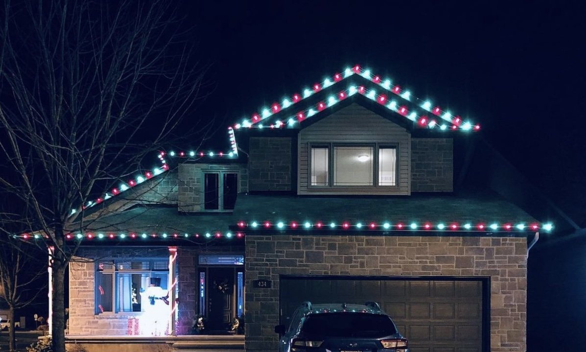 Two-story home with alternating red and green C9 Christmas roofline lights